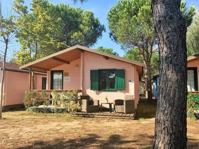 Holzchalet mit überdachter Veranda und Terrassenmöbeln auf einem schönen Campingplatz